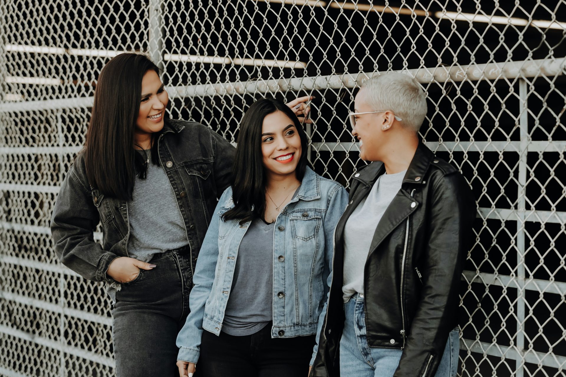 3 Frauen stehen neben einem grauen Metallzaun